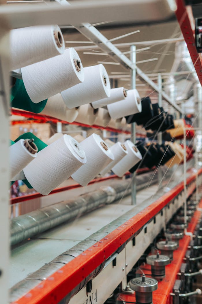 services-03 Detailed view of yarn spools in a textile factory, showcasing industrial equipment.